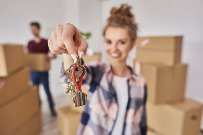 A girl holding keys while Seattle movers move boxes behind her